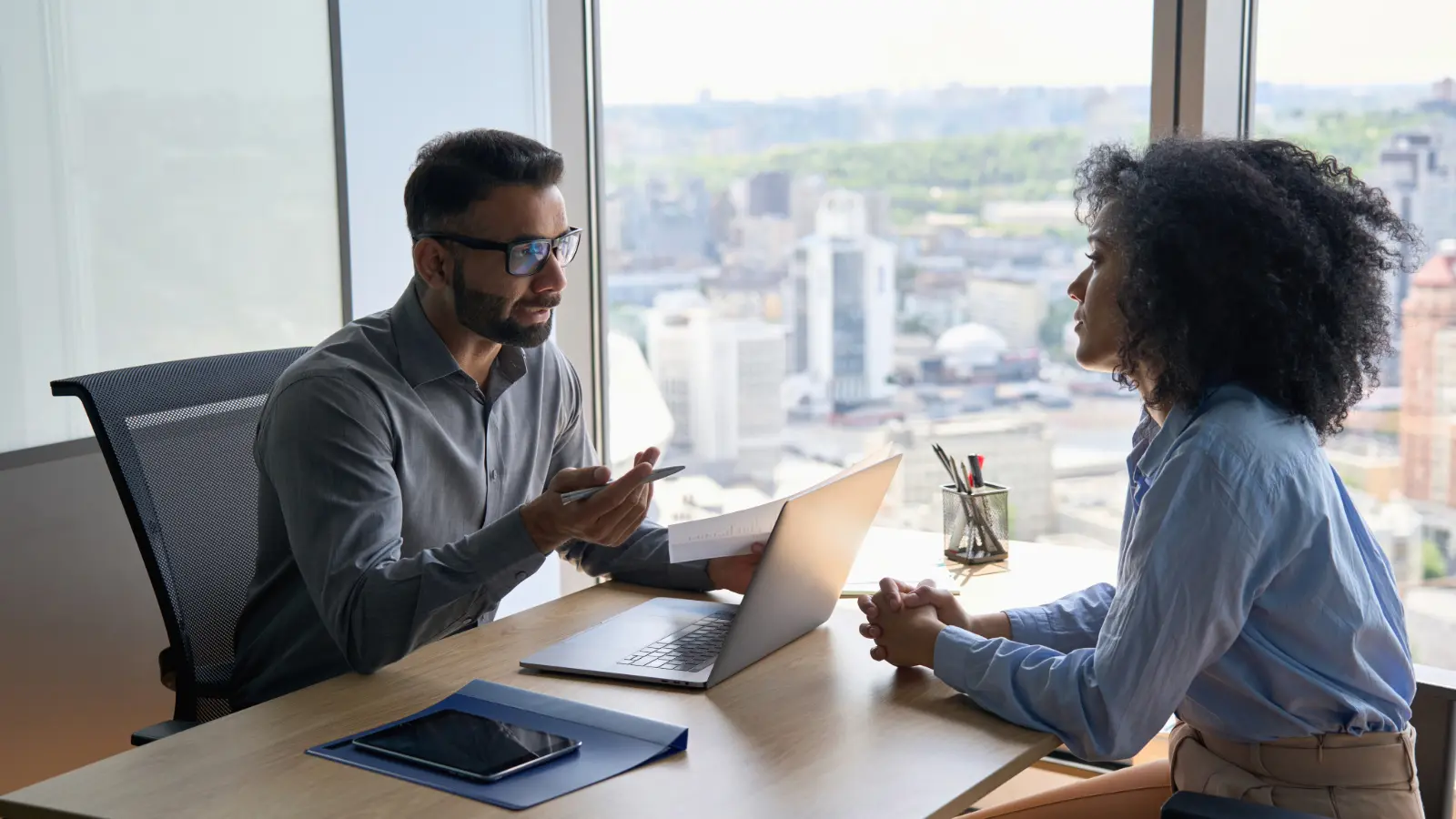 Photo of a male executive leader interviewing a female job candidate in an office setting.