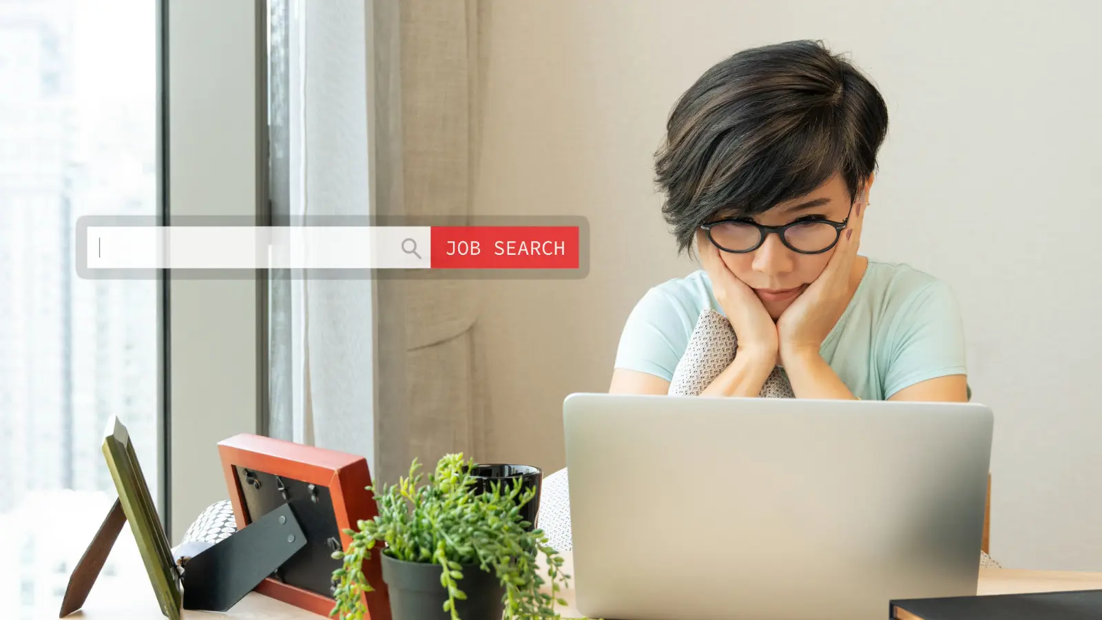 Woman job seeker looking at a laptop with her face in her hands. She looks a bit frustrated or concerned.