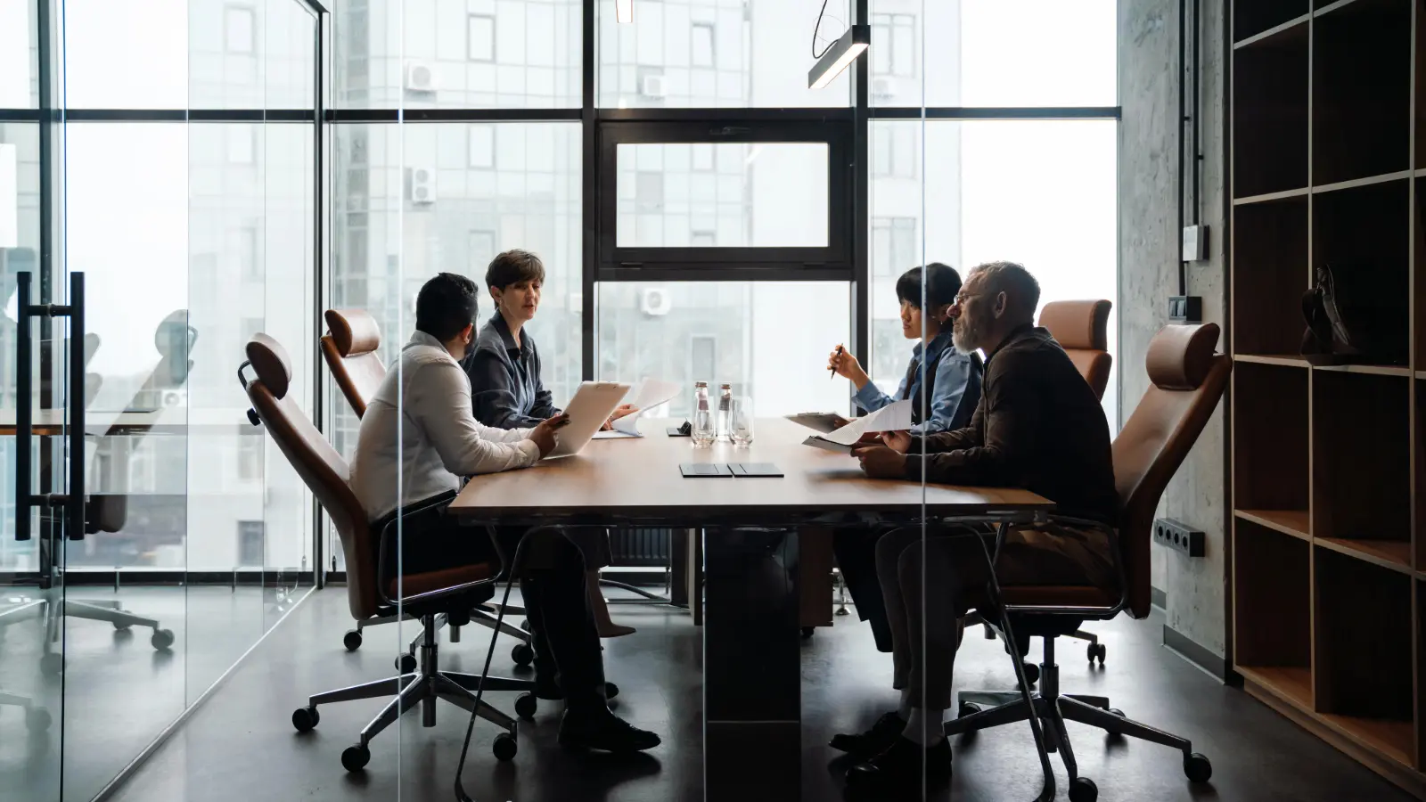 Four business people sitting at a conference table discussing a business issue.